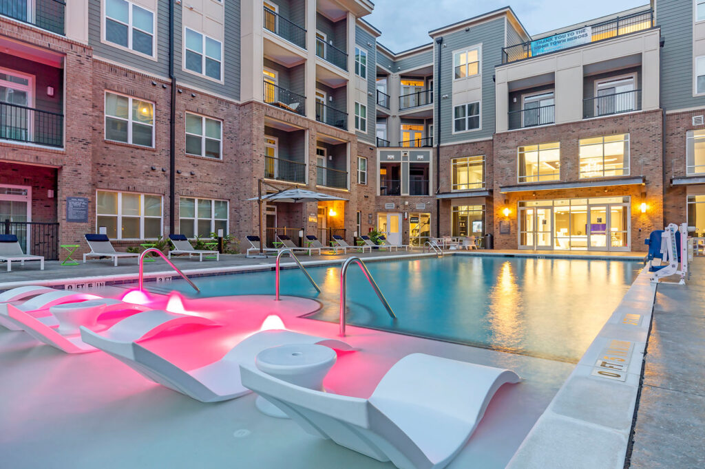 Apartment Community Pool with Pink Lights and Modern Lounge Chairs
