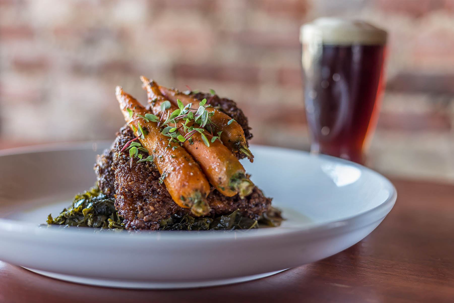 Food photography: A fancy dish topped with carrots and a beer in the background.