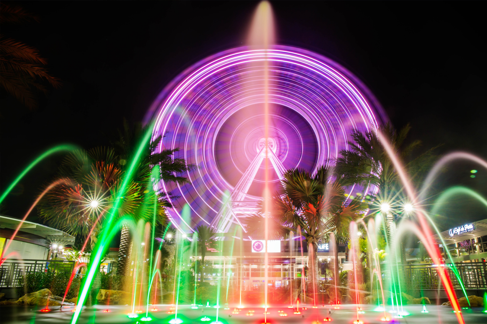 The Orlando Eye ferris wheel lit up at night in purple.