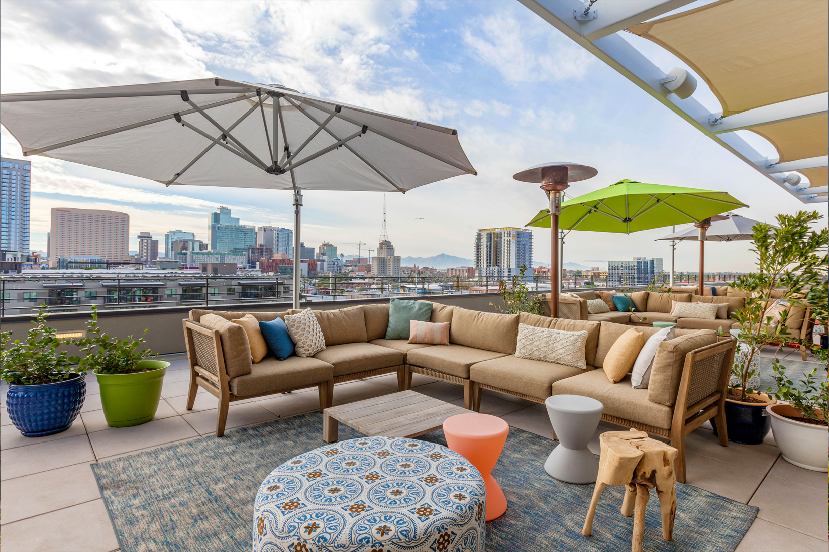 An outdoor balcony area with couches and umbrellas over looking the city of Phoenix.