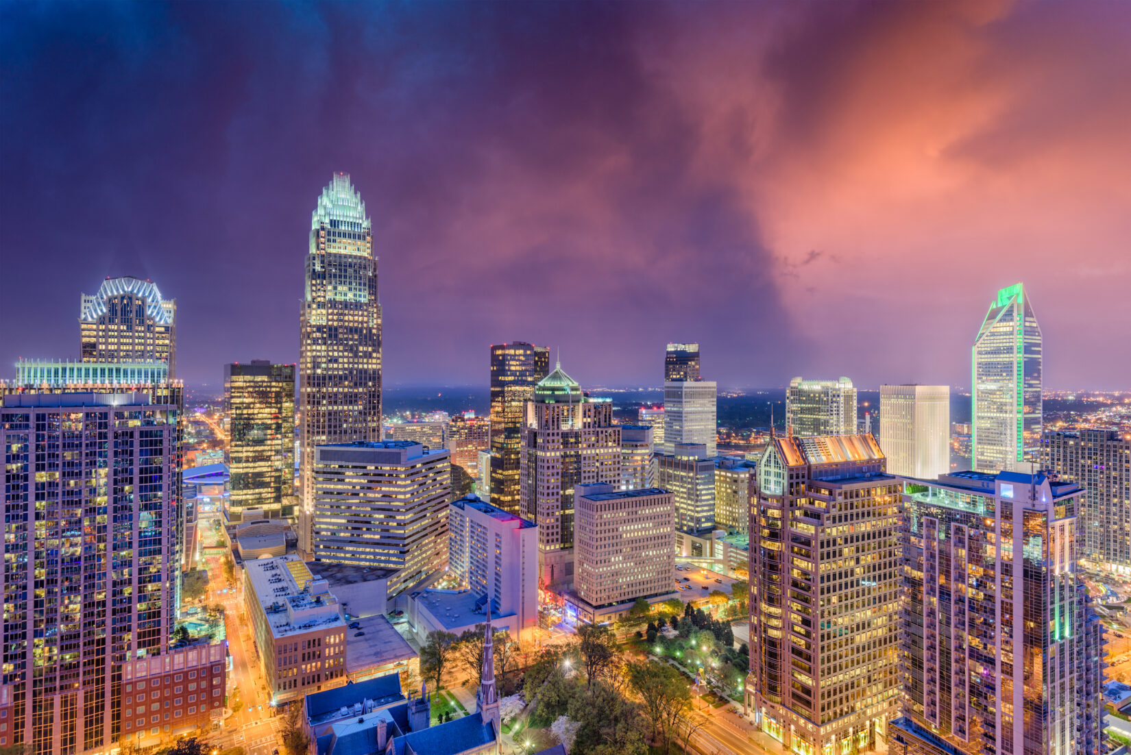 Charlotte, North Carolina city skyscrapers lit up against a colorful and vibrant sky. Charlotte real estate photography by CS3. Charlotte aerial photography.