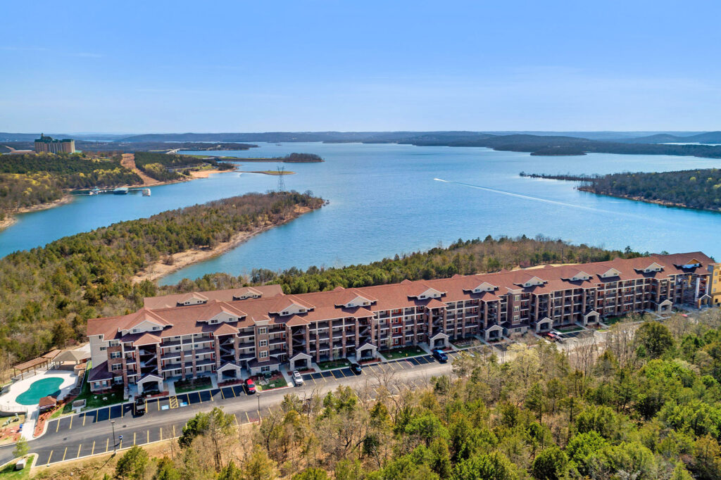 Drone view of a condominium complex on the coast of a lake.