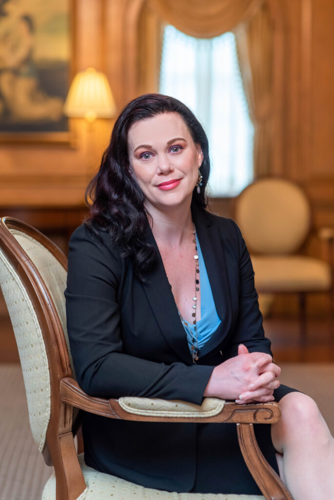 A headshot of a woman with brown hair sitting in a chair.