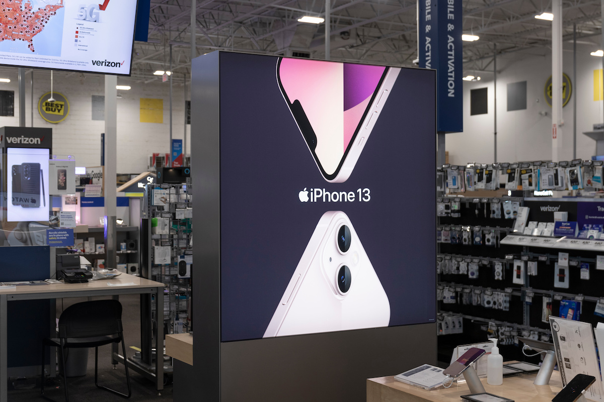 An iPhone 13 sign on display in a Best Buy store.
