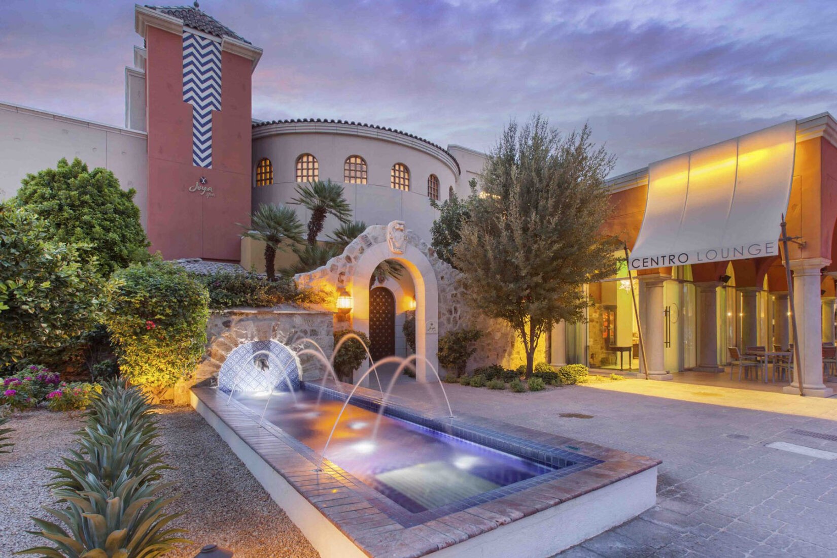 The Omni Scottsdale Resort & Spa at sunset with illuminated fountain and desert-style landscaping.