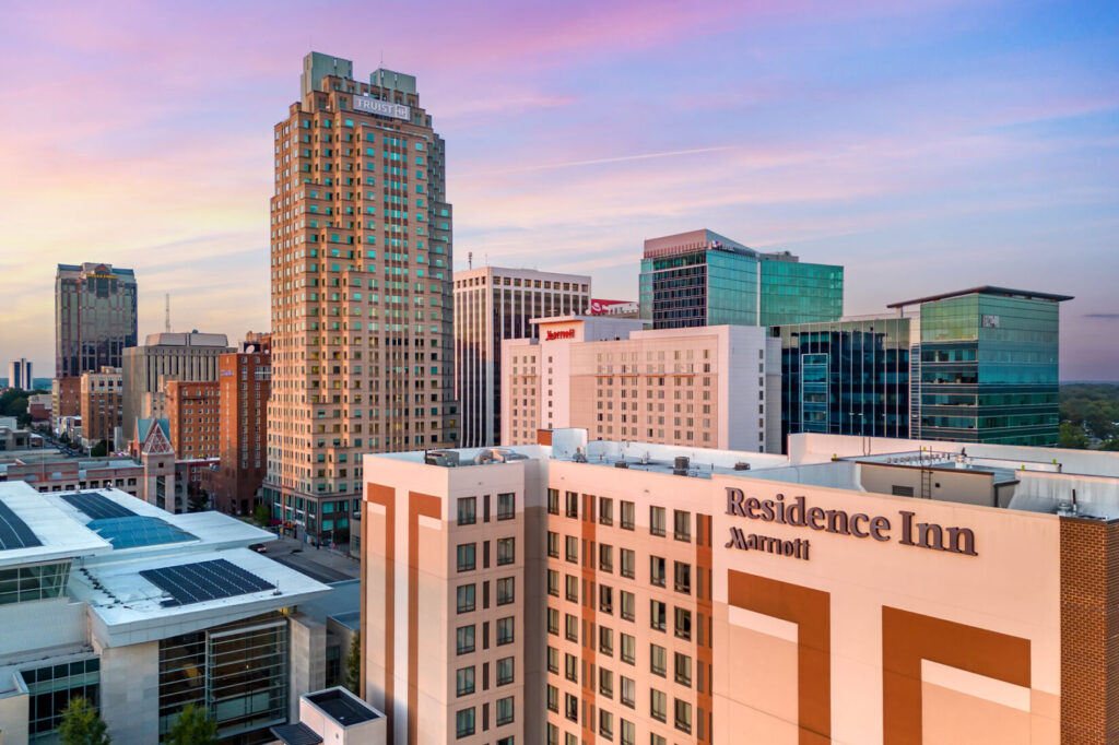 Residence Inn Raleigh Downtown exterior at sunset with city skyline in the background.